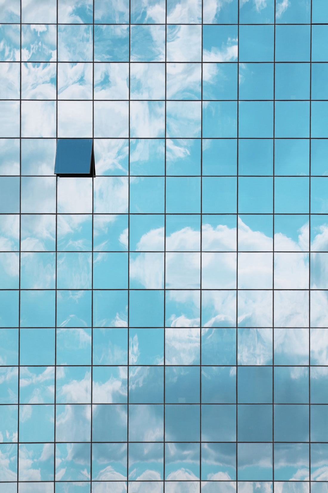Façade entièrement vitrée reflétant le ciel : des milliers de vitres à entretenir